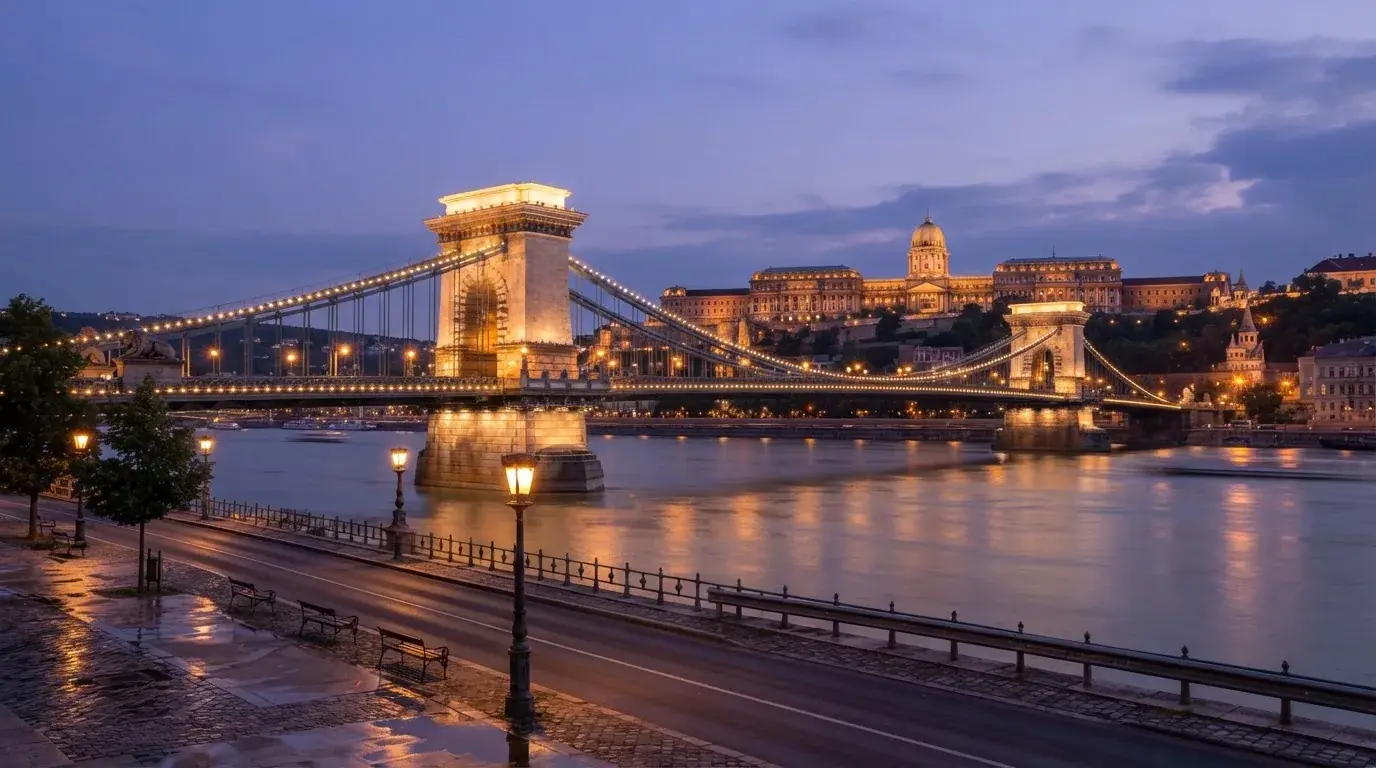 A budapesti Lánchíd esti fényekben a Duna fölött, a háttérben a budai Vár, forgalom nélküli rakpart.